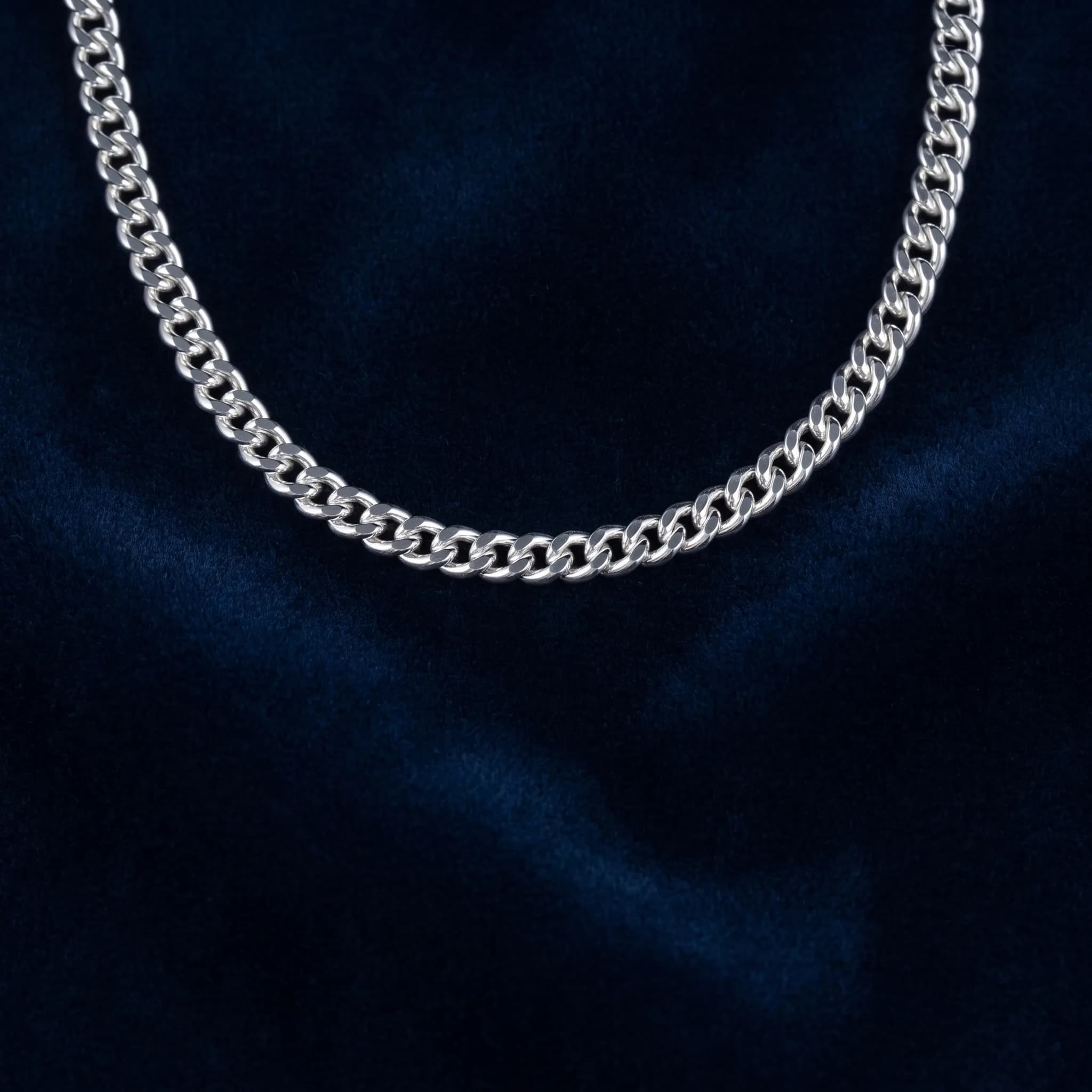 Polished sterling silver curb chain on navy blue velvet
